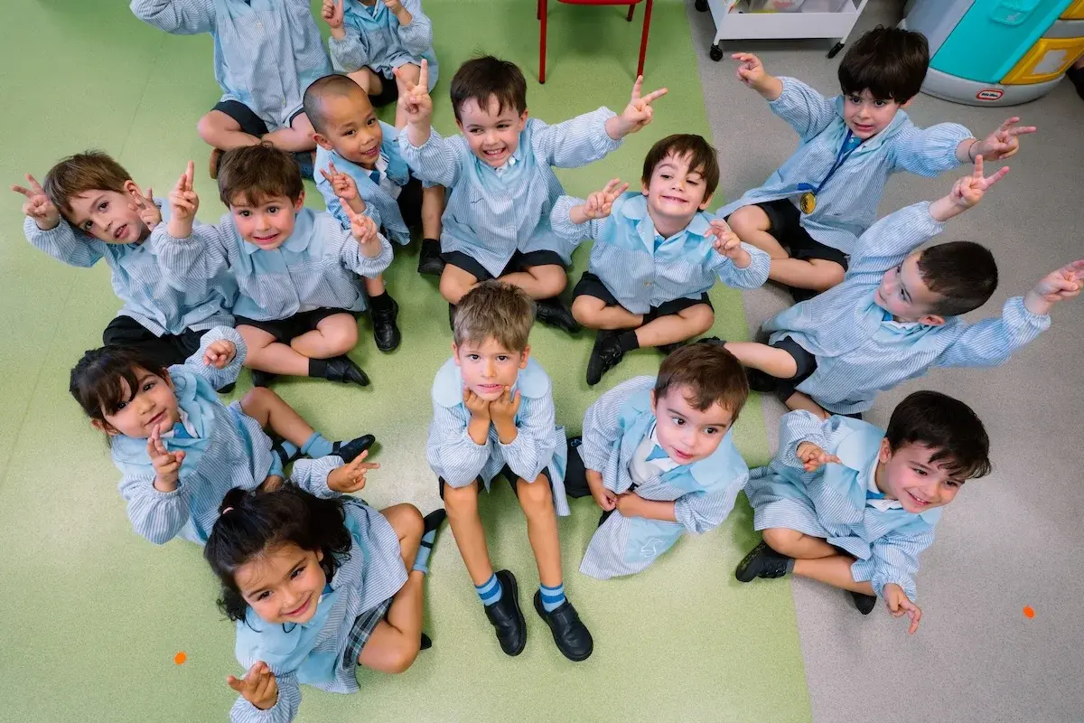 Grupo de estudiantes del Liceo Sorolla en uniforme azul posando juntos en el piso durante actividad escolar